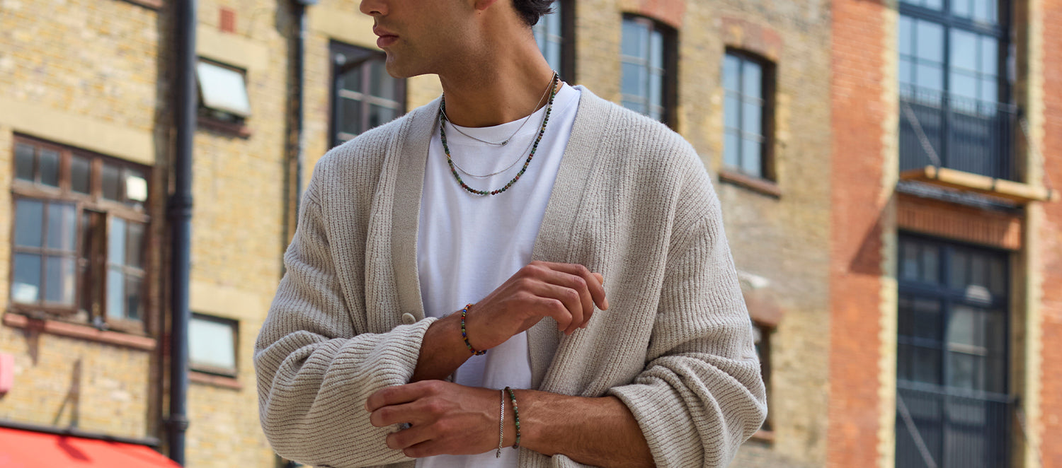 Person wearing a beige cardigan over a white shirt in an urban setting