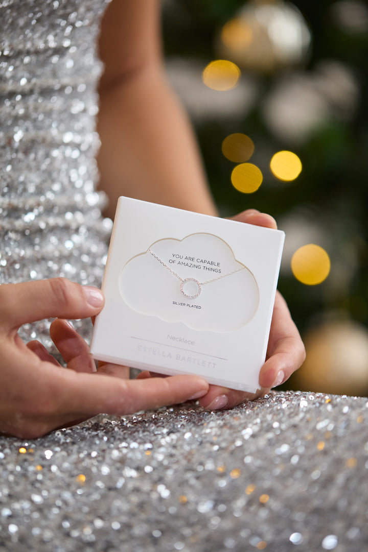 Person holding a white card with decorative text against a festive background