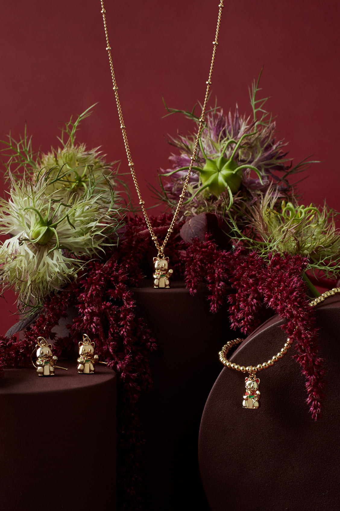 Gold necklace with pendant on a dark surface with flowers