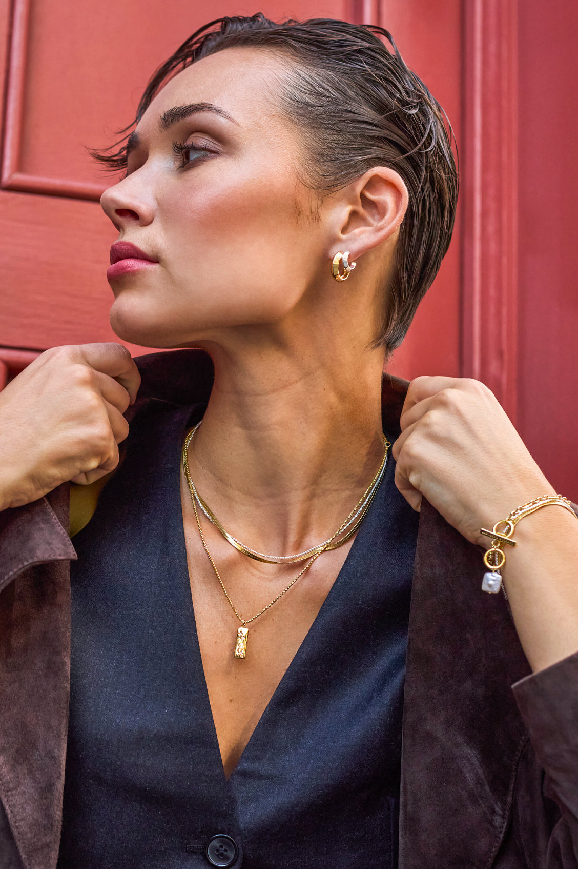 Woman wearing gold jewelry against a red background