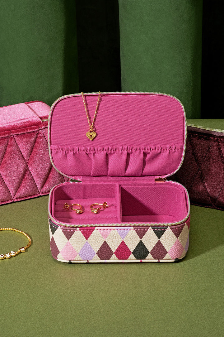 Pink jewelry case with gold jewelry on a green background