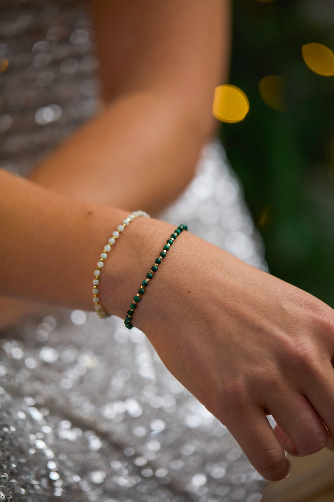 Close-up of a hand wearing two bracelets with a blurred background