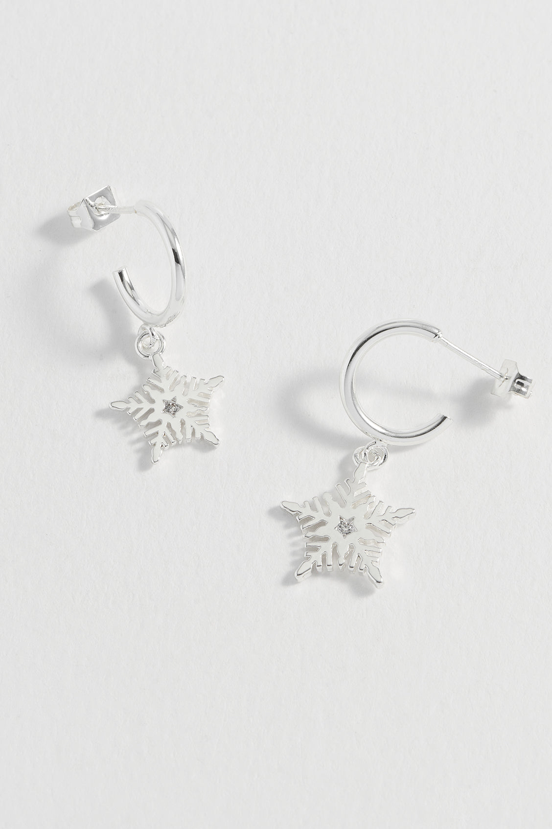 Silver snowflake earrings on a light gray background