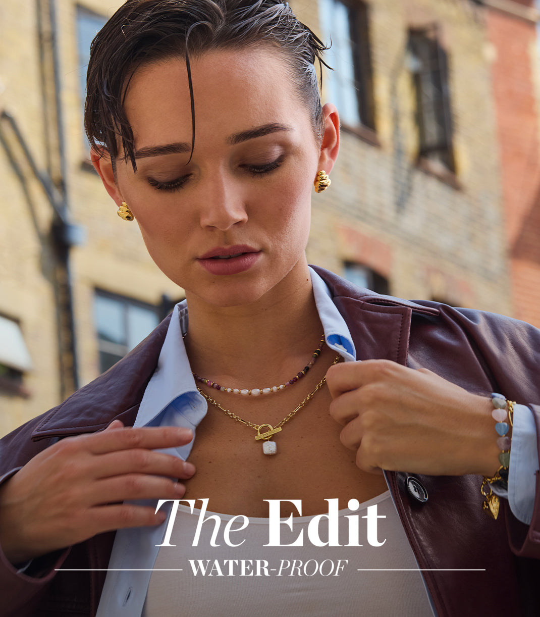 Woman adjusting her jacket with a blurred urban background, featuring 'The Edit' text.