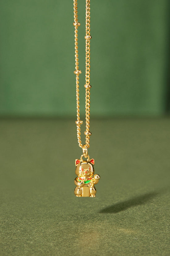 Gold necklace with a small pendant on a green background