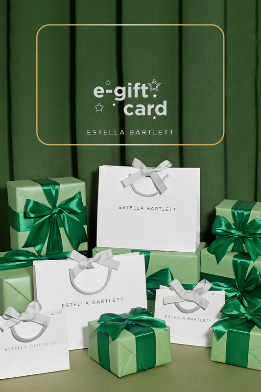Green gift boxes and bags with 'Estella Bartlett' branding on a green background.